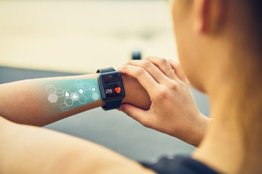 Young woman checking the sports watch with screen healthcare icon, measuring heart rate and performance after running.